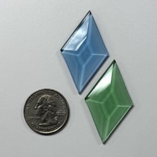 Two translucent diamond-shaped blue and green glass beads placed near a US quarter for scale.
