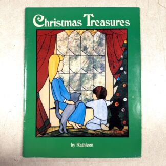 Green book cover titled 'Christmas Treasures' by Kathleen, featuring a woman, child, cat, and Christmas tree beside a stained-glass window.