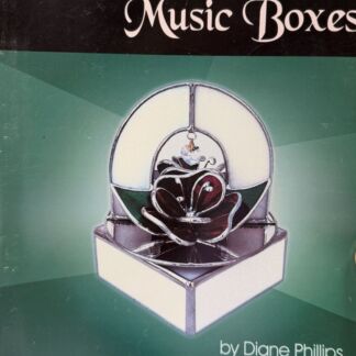 Cover of a book titled 'Enchanted Music Boxes' featuring a glass musical box with a white rose, on a green gradient background, by Diane Phillips