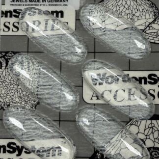 Close-up of clear capsule-like objects scattered on a patterned background with a label reading 'No. 4518 - Clear Jewels Made in Germany'.